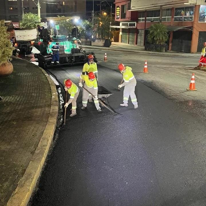 Equipe de obras realizando restauração em asfalto durante a noite.
