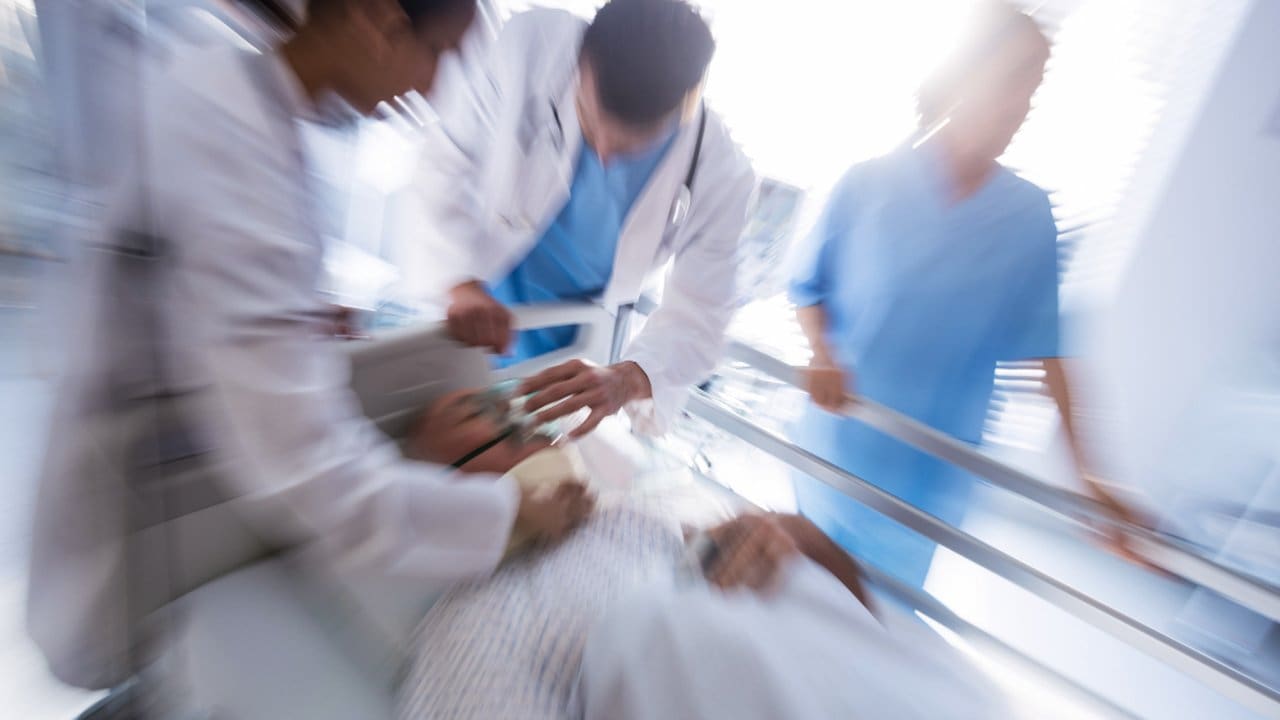Equipe médica socorrendo paciente em maca em ambiente hospitalar.