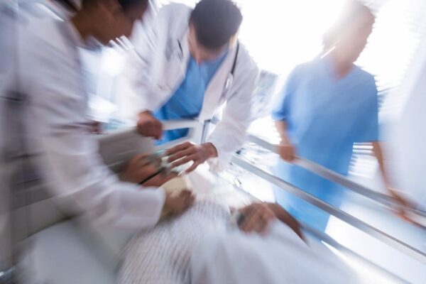Equipe médica socorrendo paciente em maca em hospital.