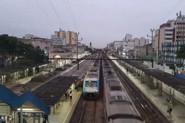 Estação de trem em dia nublado com trens estacionados e prédios ao fundo