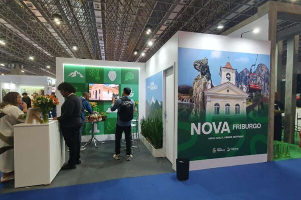 Estande de Nova Friburgo na ABAV Expo 2025, com imagem da cidade e pessoas.