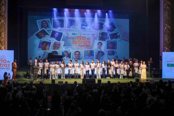 Estudantes premiados no Prêmio Rio de Letras Firjan SESI no Theatro Municipal, com logos e telão de fundo.