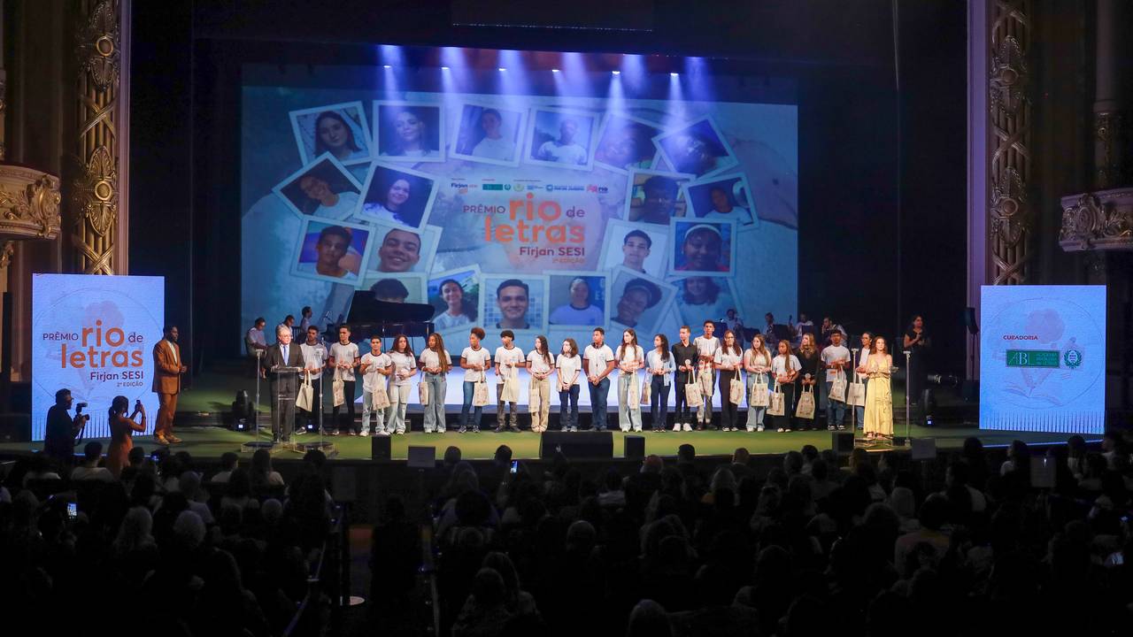 Estudantes premiados no Prêmio Rio de Letras Firjan SESI no Theatro Municipal, com logos e telão de fundo.