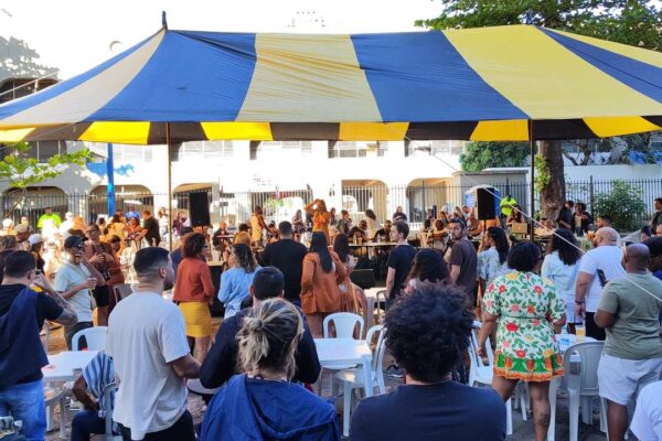 Evento Samba da Feira com roda de samba e público reunido sob tenda colorida.