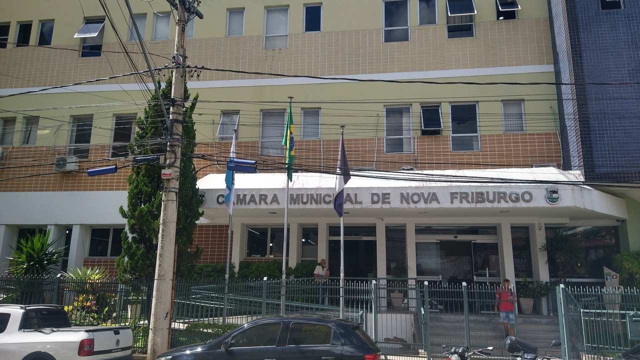 Fachada da Câmara Municipal de Nova Friburgo, com bandeiras hasteadas.