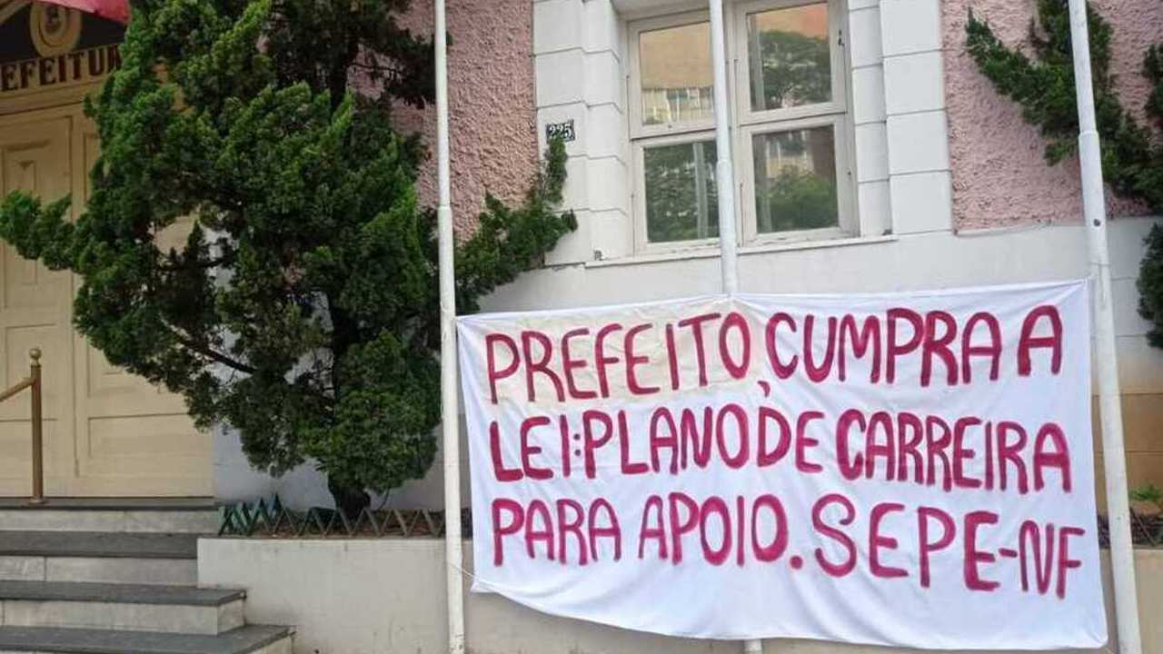Faixa com mensagem de protesto de professores em frente à prefeitura.