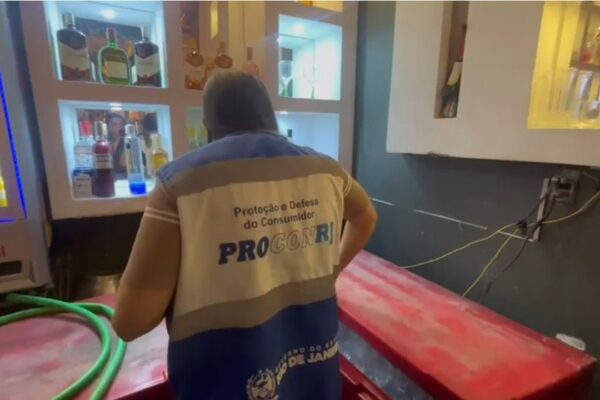 Fiscal da ProconRJ durante operação em bar, com bebidas expostas e fiscalização.