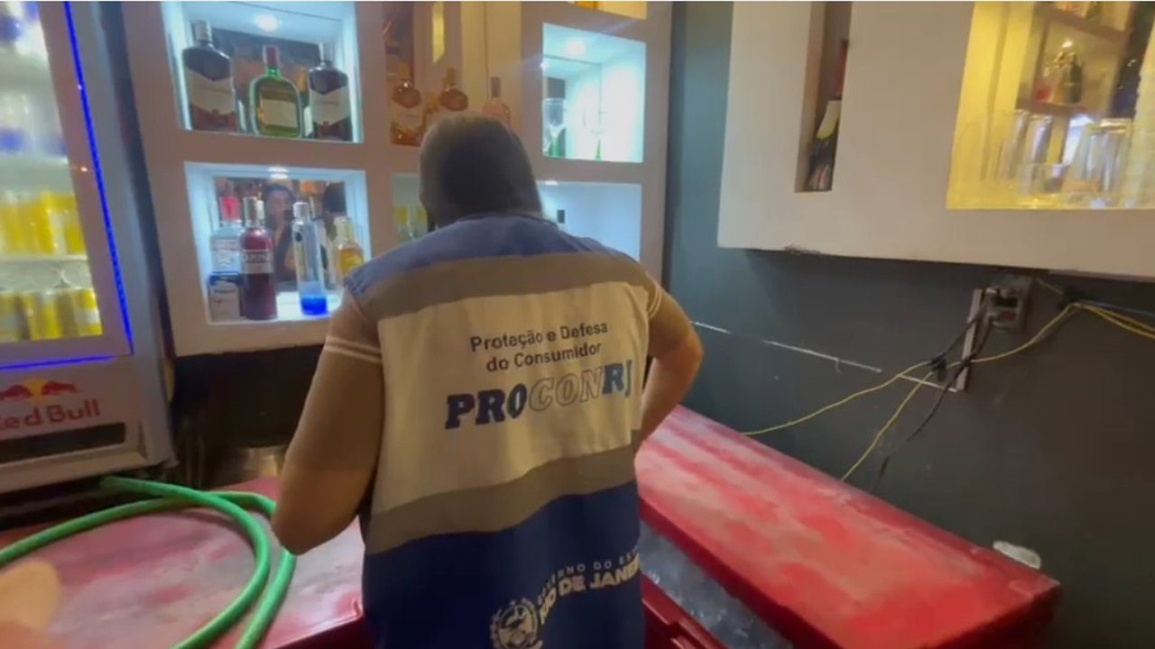 Fiscal da ProconRJ durante operação em bar, com bebidas expostas e fiscalização.