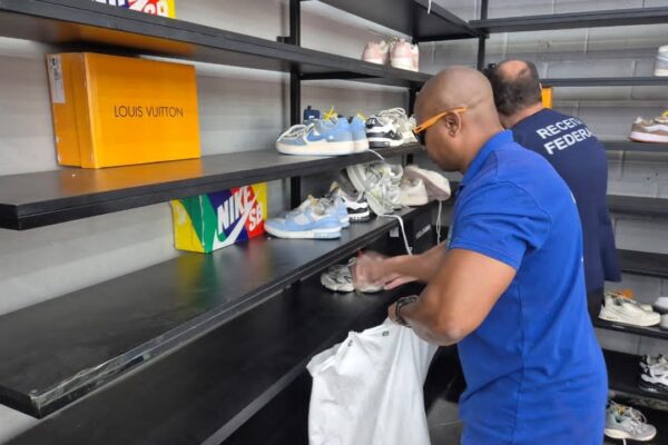 Fiscalização em loja de artigos de luxo no Rio de Janeiro, com caixas e tênis em prateleiras.