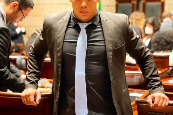 Gabriel Monteiro em sessão, usando paletó preto e gravata clara, com olhar sério.