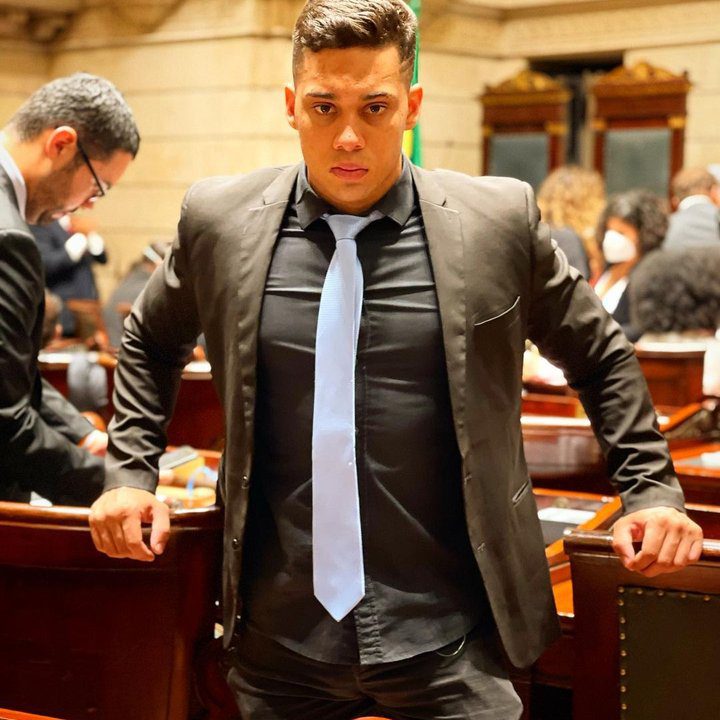 Gabriel Monteiro em sessão, usando paletó preto e gravata clara, com olhar sério.