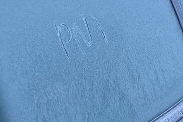 Geada cobrindo o vidro de um carro no Parque Nacional do Itatiaia, com as letras 'PM' escritas.