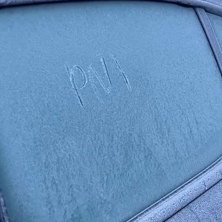 Geada cobrindo o vidro de um carro no Parque Nacional do Itatiaia, com as letras 'PM' escritas.