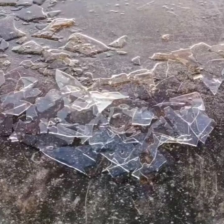 Gelo fragmentado sobre superfície escura, representando geada na paisagem.