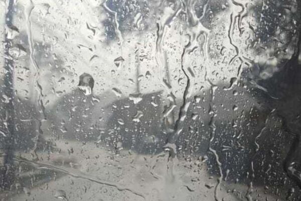 Gotas de chuva em vidro, reflexo de ambiente nublado.