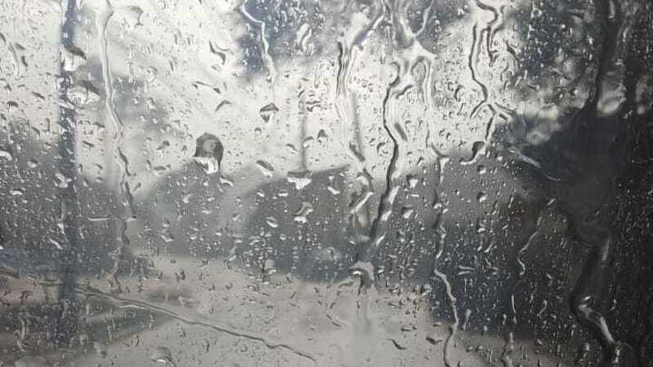 Gotas de chuva em vidro, reflexo de ambiente nublado.