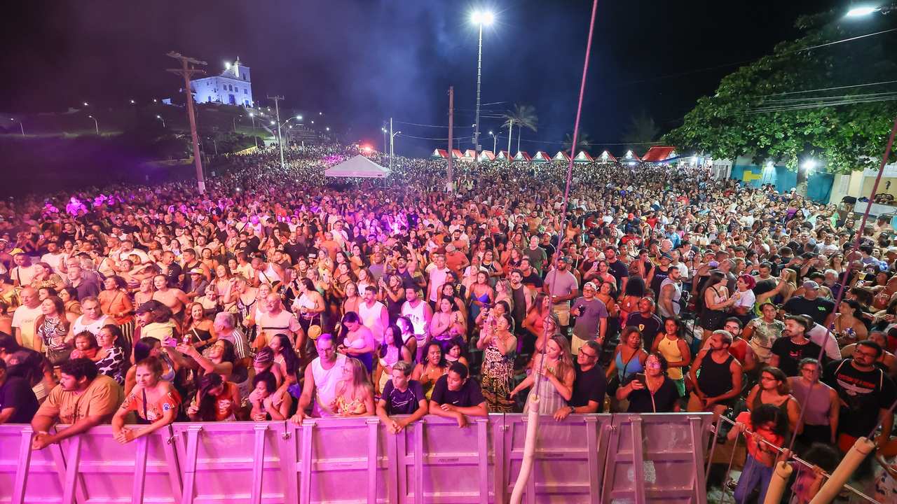 Grande público reunido em festival de verão em Saquarema, Brasil, à noite.