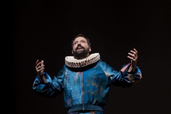 Gregório Duvivier em cena da peça Céu da Língua, usando figurino teatral azul e gola de babado.