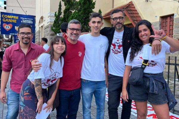 Grupo de pessoas em manifestação em Nova Friburgo, com camisetas e bandeiras.