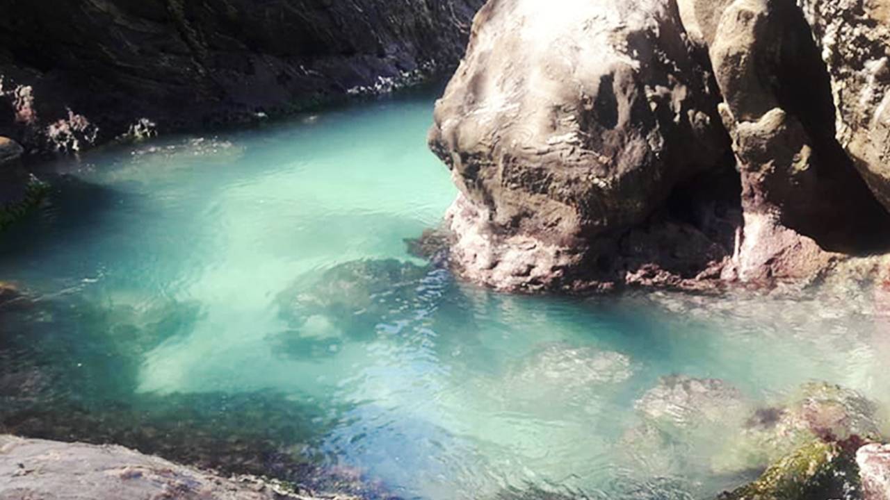 Gruta Ponta Negra em Maricá com água azul turquesa e rochas.