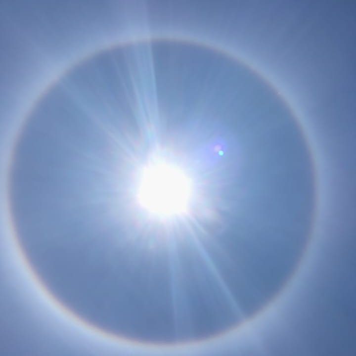 Halo solar em Nova Friburgo, com o sol brilhando no centro e um arco-íris circular.