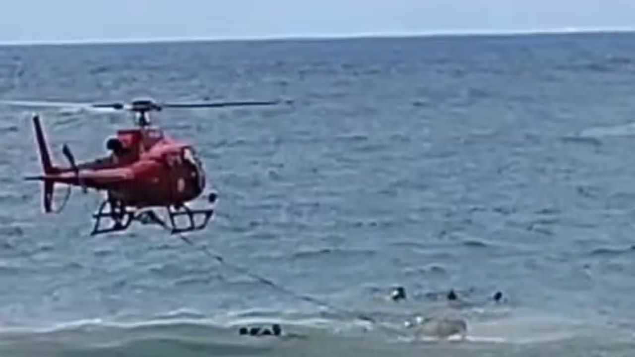 Helicóptero de resgate sobrevoa o mar com vítimas na água, em Itaipuaçu, Maricá.