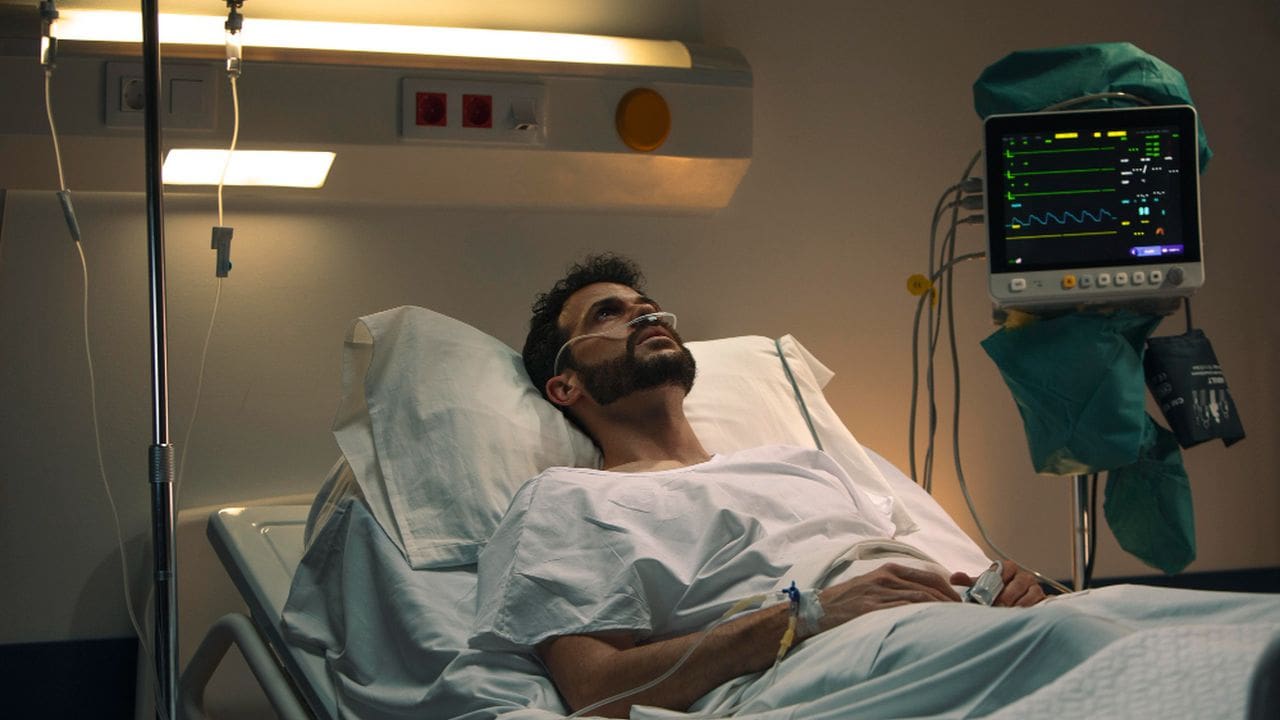 Homem em leito de hospital com máscara de oxigênio, monitor de sinais vitais e soro.