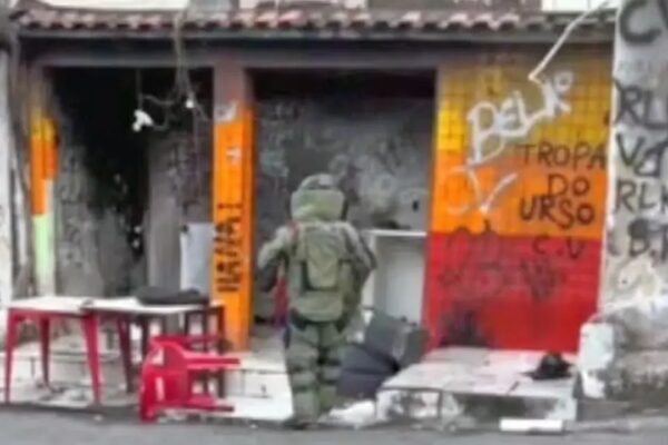 Homem em traje antibomba entra em uma área com grafites no Rio de Janeiro.