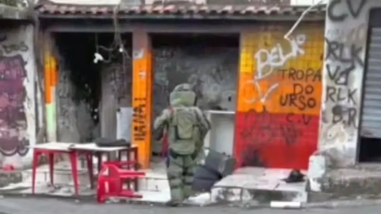 Homem em traje antibomba entra em uma área com grafites no Rio de Janeiro.