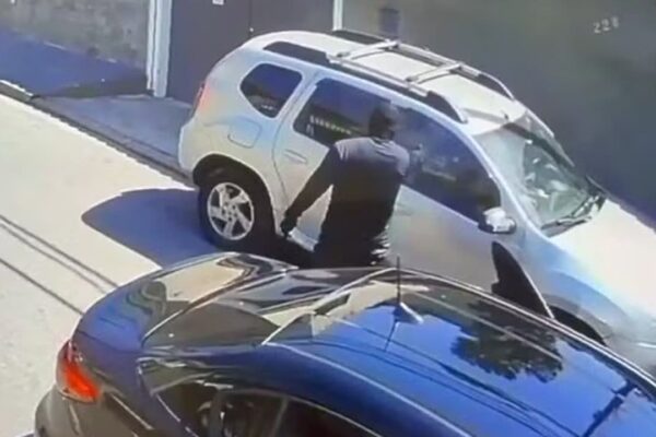 Homem encapuzado tentando entrar em carro.