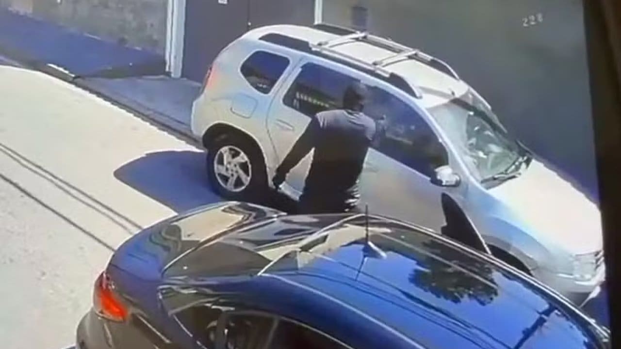 Homem encapuzado tentando entrar em carro.