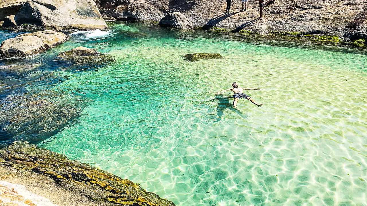 Homem relaxando nas águas cristalinas da Praia do Secreto, Rio de Janeiro.