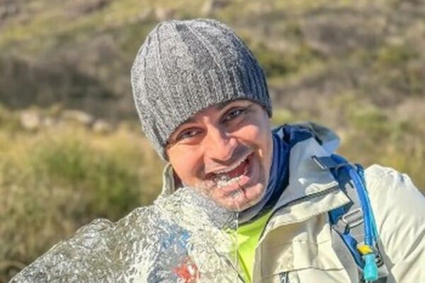 Homem segurando bloco de gelo com sorriso em Itatiaia, em noite de frio recorde.