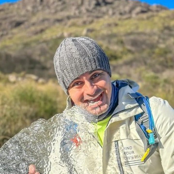 Homem segurando bloco de gelo com sorriso em Itatiaia, em noite de frio recorde.