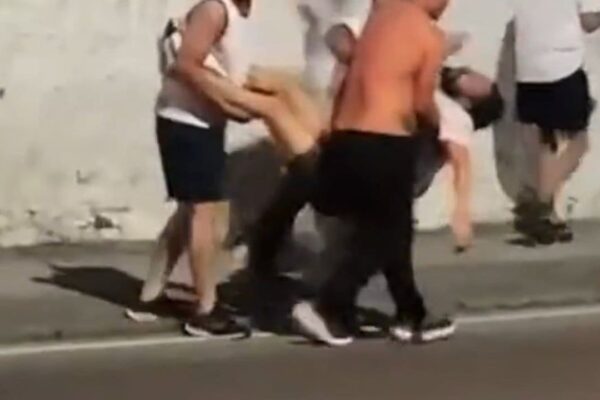 Homens carregam pessoa desacordada em meio a confusão.