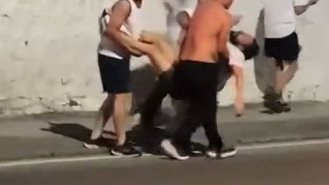 Homens carregam pessoa desacordada em meio a confusão.