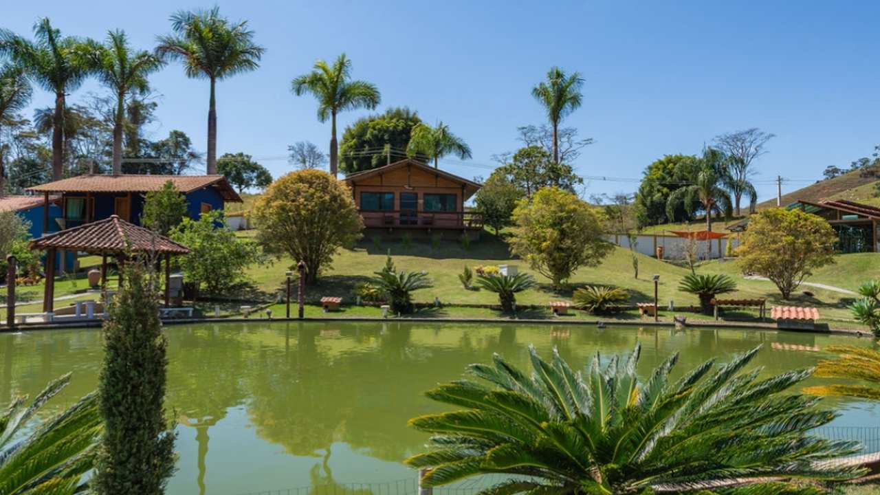 Hotel em Bom Jardim, Rio de Janeiro, com lago e vegetação exuberante, em dia ensolarado.