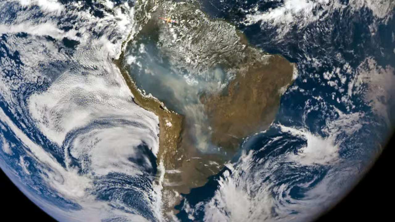 Imagem de satélite mostrando a América do Sul, com nuvens e uma grande quantidade de fumaça sobre o continente.