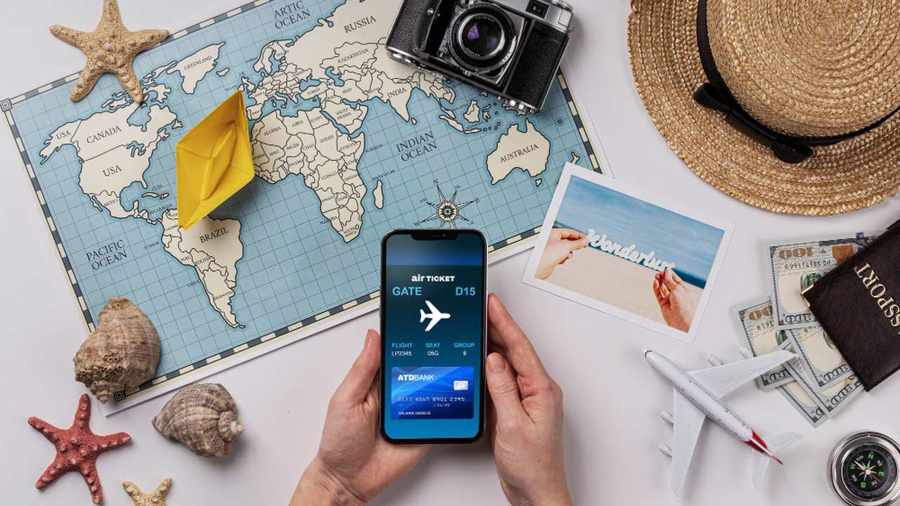 Imagem de viagem com mapa, celular com passagem aérea e outros objetos turísticos.