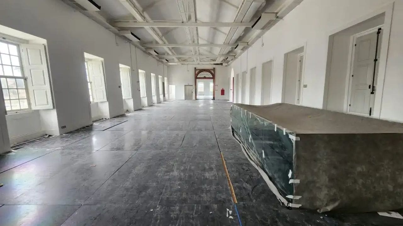 Interior do museu histórico com janelas, portas e objetos cobertos.