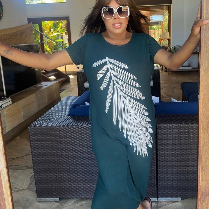 Jadler Silva em imagem de divulgação, trajando vestido com estampa de folha e óculos de sol.