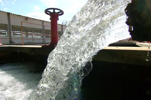 Jato de água jorrando de uma tubulação em uma estação de tratamento.