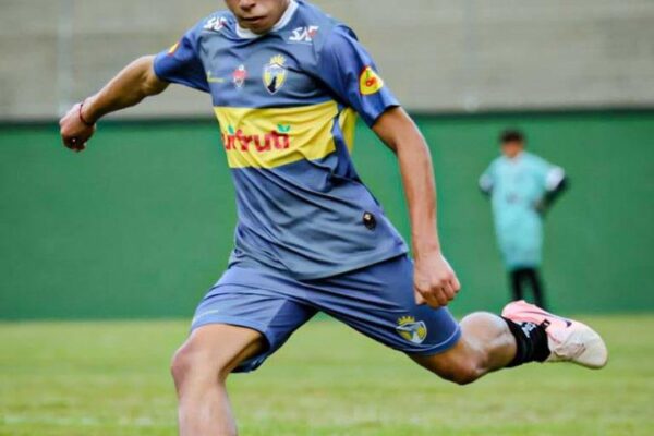 Jogador de futebol Friburgo Sporting chutando a bola em partida.
