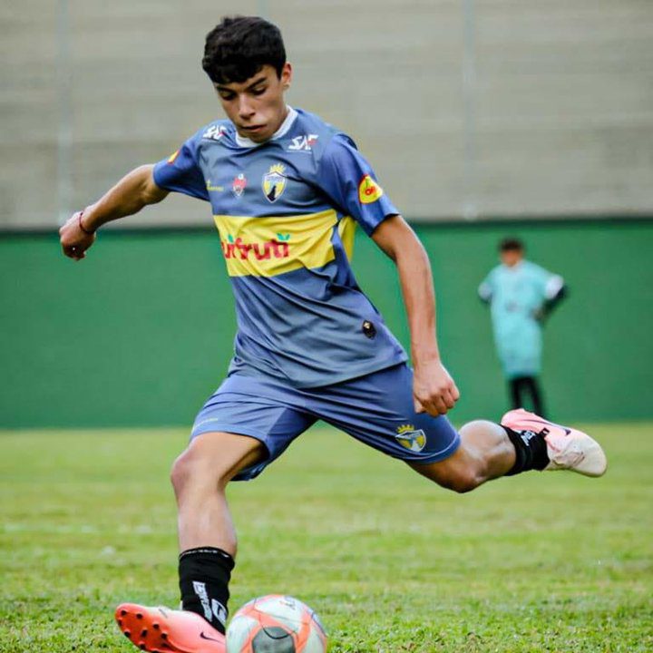 Jogador de futebol Friburgo Sporting chutando a bola em partida.