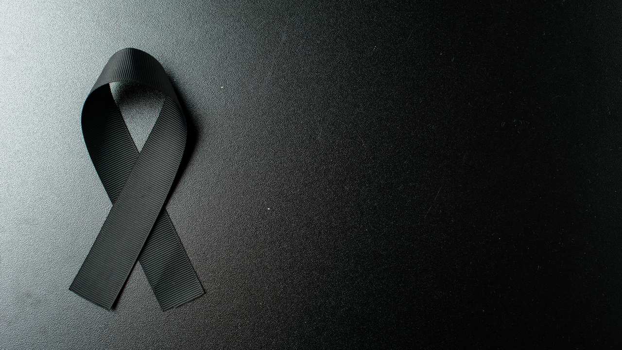 Laço preto de luto sobre fundo escuro.