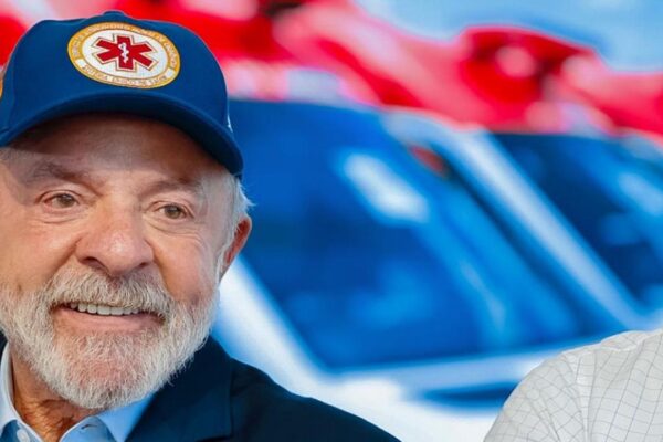 Lula sorrindo usando boné azul com logotipo em evento político