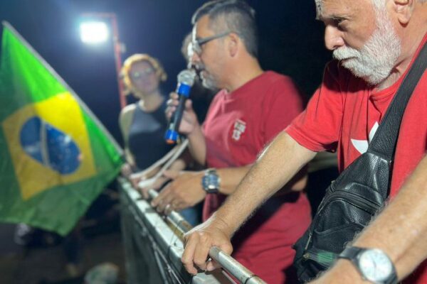 Manifestação em Nova Friburgo em apoio à democracia, com bandeira do Brasil e pessoas falando.