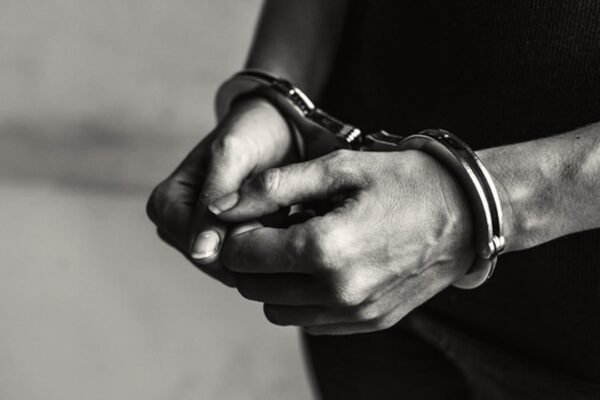 Mãos algemadas em preto e branco, simbolizando prisão e crime.