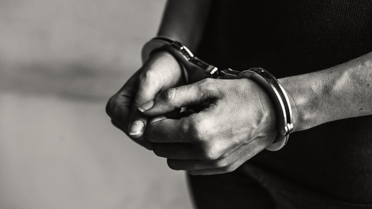 Mãos algemadas em preto e branco, simbolizando prisão e crime.