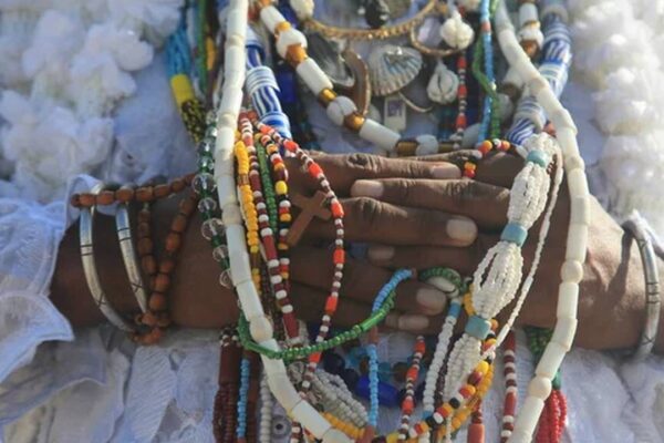 Mãos com contas e colares coloridos, em cerimônia religiosa de Umbanda.